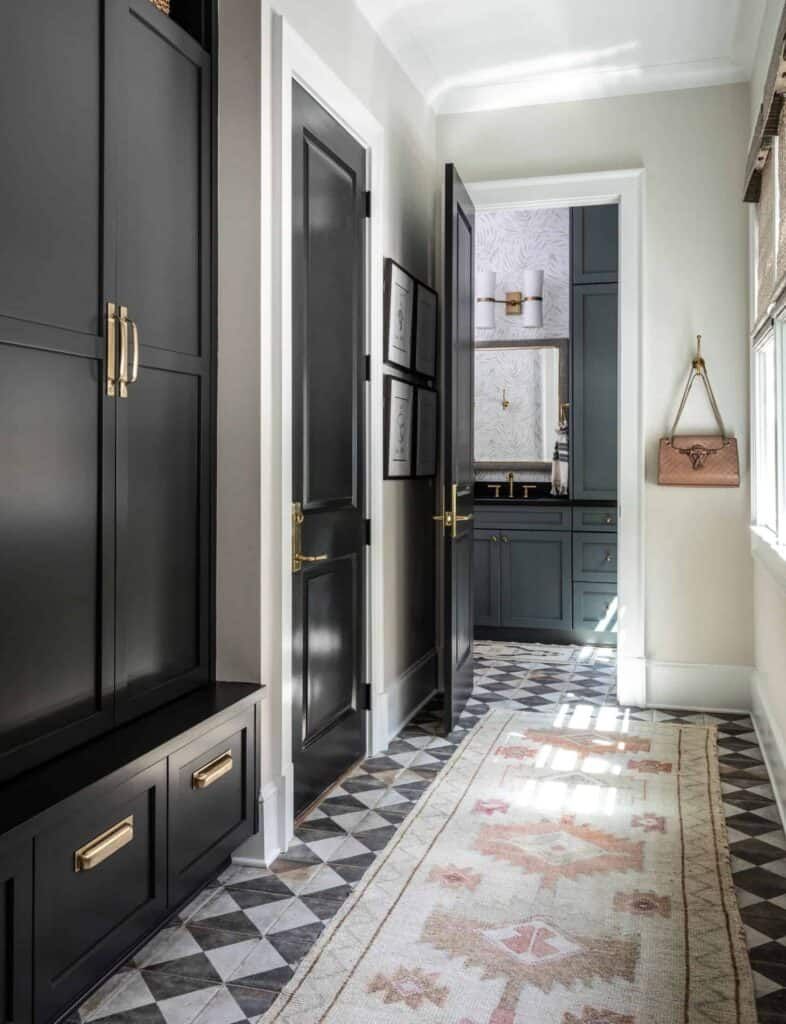 Hallway with distressed checkered flooring, a tan Turkish rug, and black cabinets.