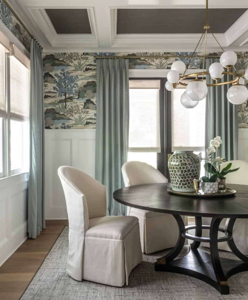 Southern dining with patterned nature-inspired wallpaper, bubble chandelier, and black round dining table.