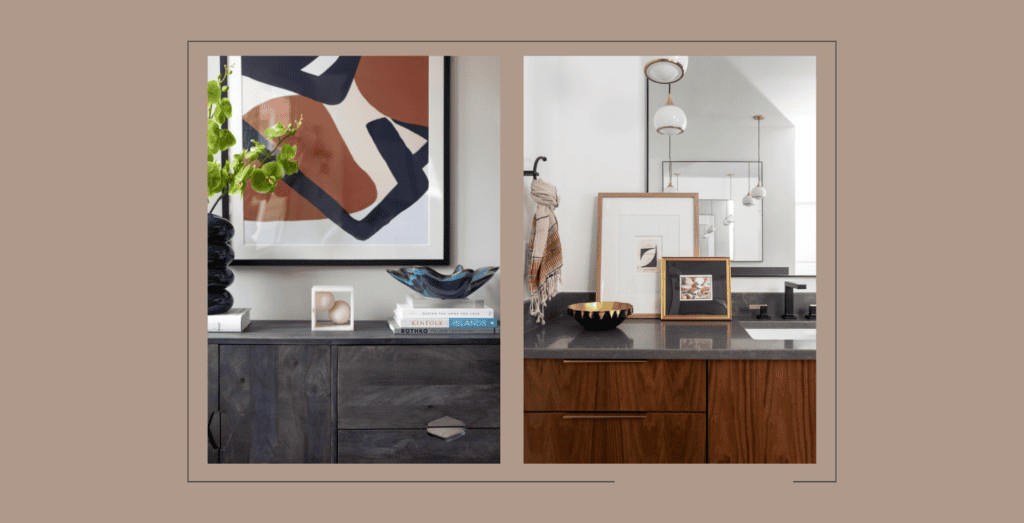 Close up of brown and black abstract painting and framed art sitting on black bathroom countertop.