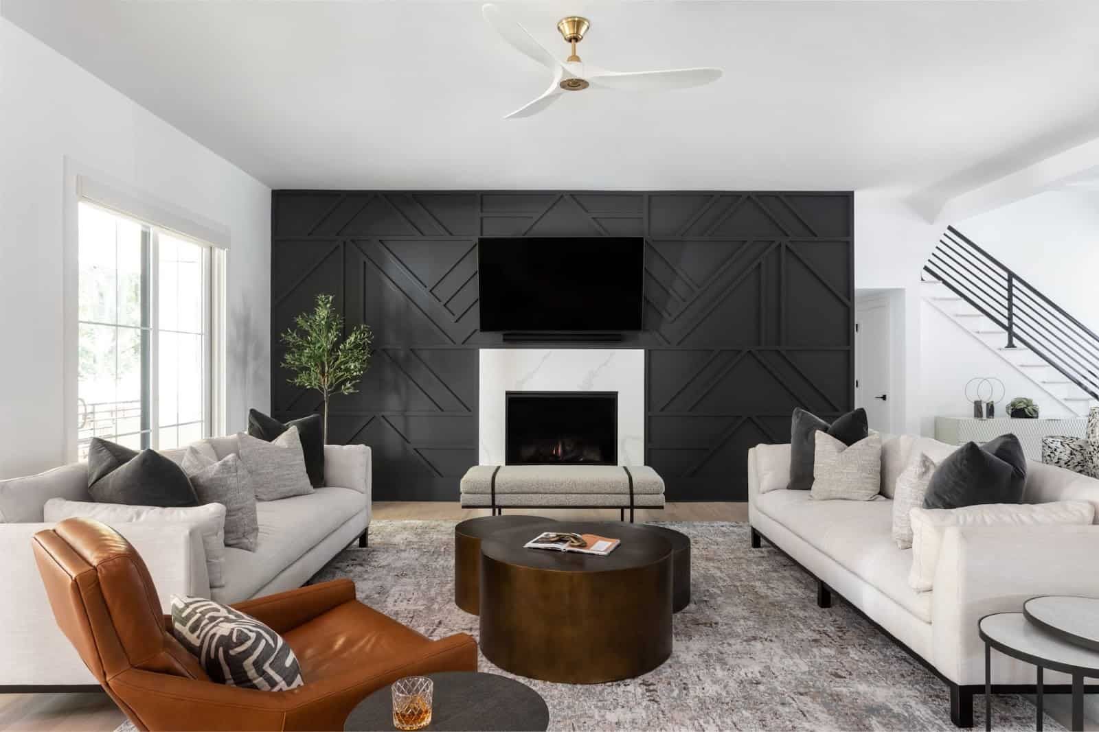 Luxury minimalist living room with leather chair and dark wood coffee table. On either side of room are twin white sofas with off-white performance fabric and dark stain legs. Z & Co. sources custom furniture in Atlanta for its clients.