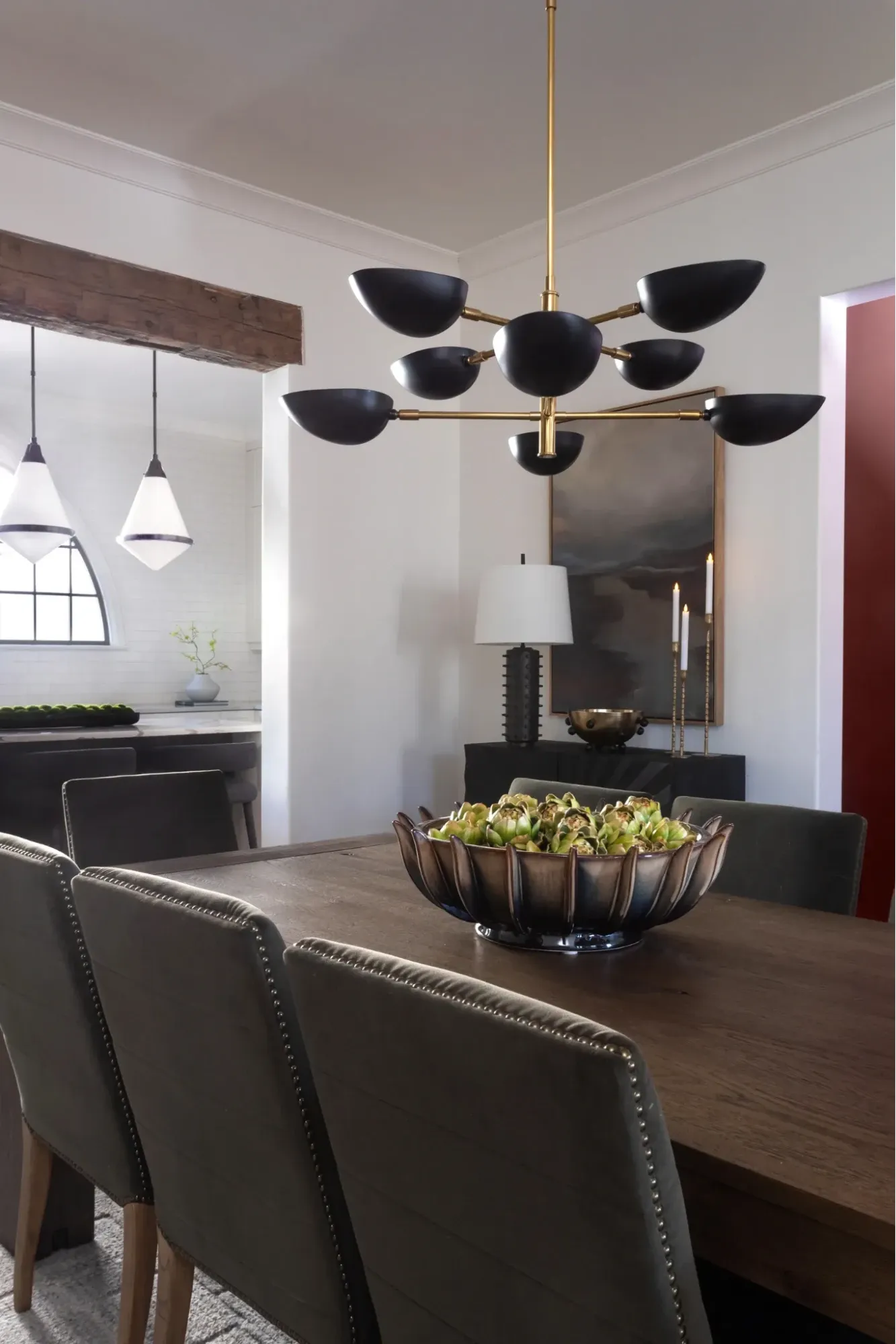 Contemporary dining room featuring a sculptural black statement chandelier, dark wood dining table, and upholstered chairs.