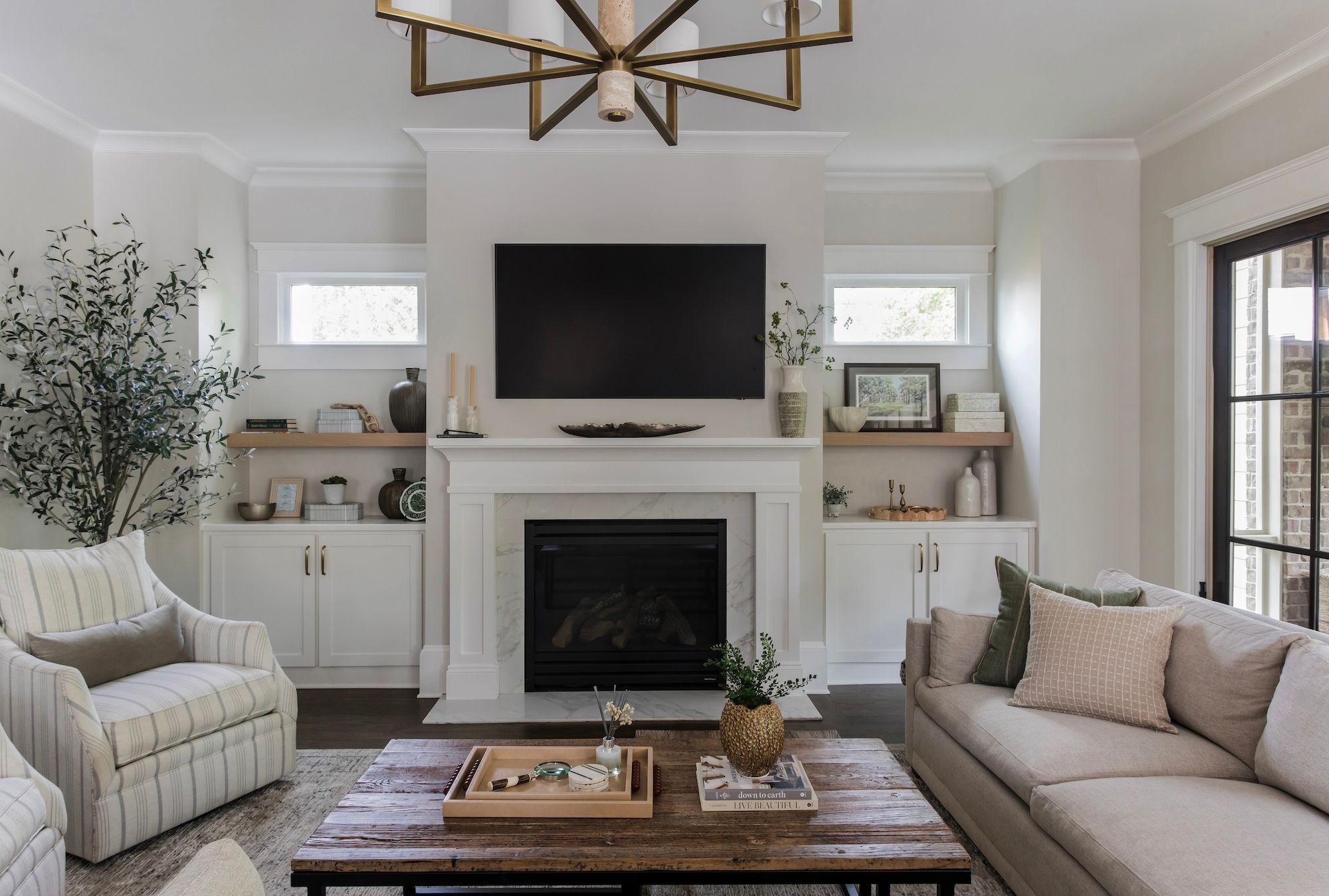 Living room with square wood coffee table, fireplace, shelving, and white walls. 