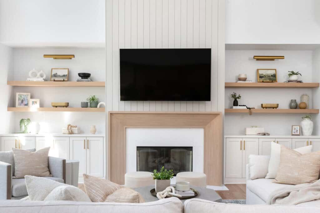 Living room with decor adorning built-in shelves on either side of a fireplace with TV above.